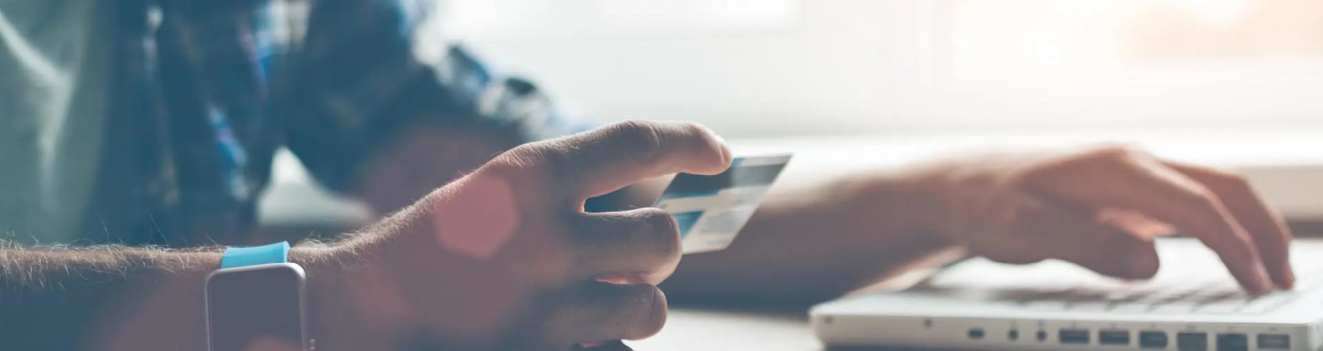 A man typing a Debit Card number into a laptop.