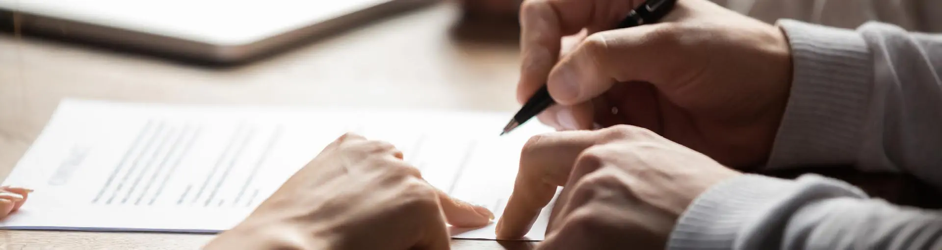 Two people reviewing and signing a document together.