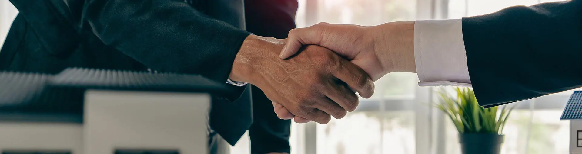 Two people shaking hands in an office setting, representing a business deal or agreement.