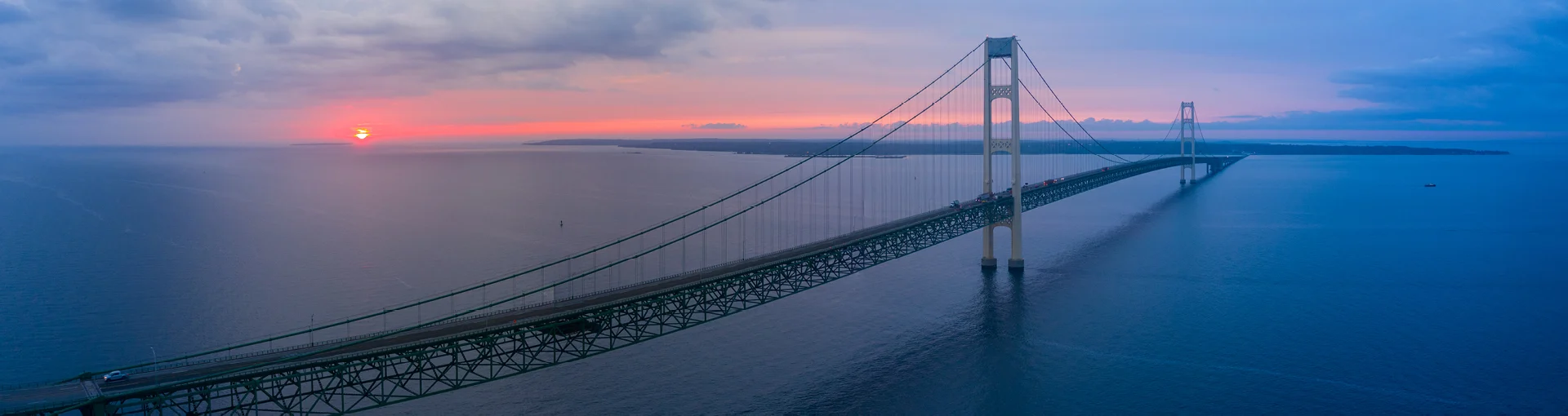 sunset on horizon aerial photo of mackinac bridge