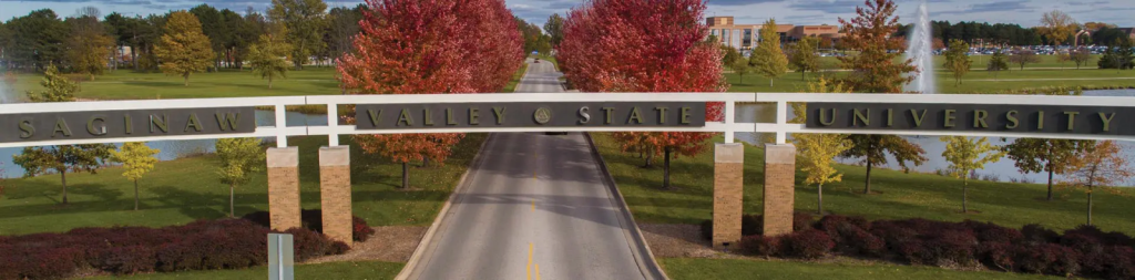 Entrance archway to Saginaw Valley State University with fall trees and campus buildings in the background.