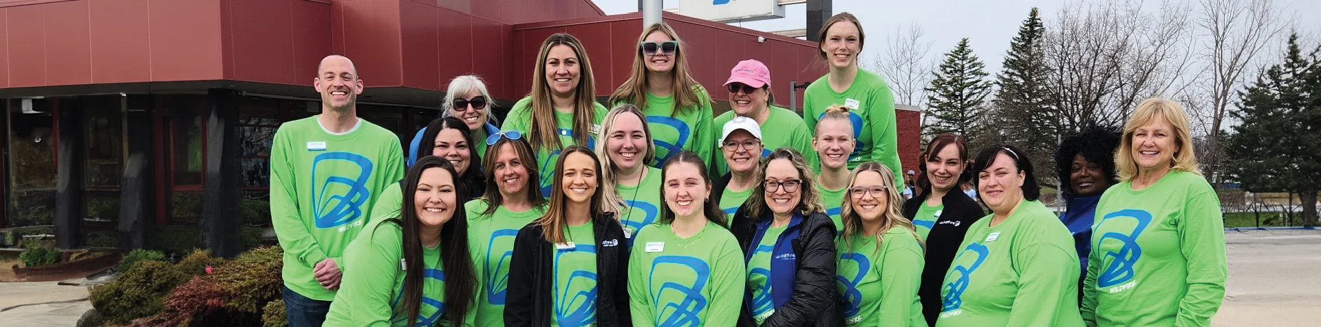 Wildfire employees wearing green logo shirts outside Saginaw YMCA.